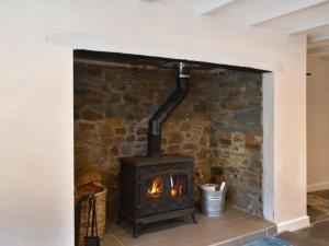 a wood stove in a room with a stone wall at Uk47758 - Horseshoe Cottage in Launceston