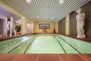 a swimming pool in a hotel with statues on the wall at Toni's Alpine Loft & SPA in Kandersteg +47 photos