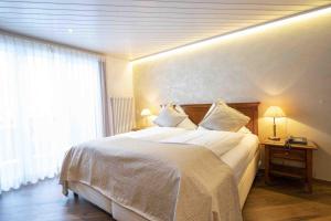 a hotel room with a large bed and a window at Toni's Alpine Loft & SPA in Kandersteg