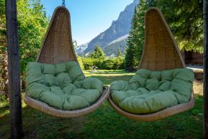 two swing chairs sitting on the grass in a yard at Toni's Alpine Loft & SPA in Kandersteg