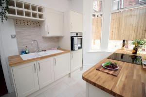 a kitchen with white cabinets and a bowl of fruit on a counter at Cathedral House by Tŷ SA in Newport +17 photos