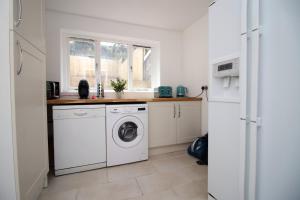 a white kitchen with a washer and dryer in it at Cathedral House by Tŷ SA in Newport