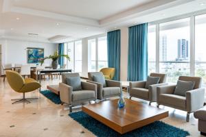 a living room with chairs and a table and windows at Hilton Cartagena in Cartagena de Indias