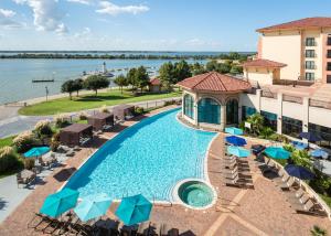 an image of a pool at a resort with chairs and umbrellas at Hilton Dallas/Rockwall Lakefront Hotel in Rockwall