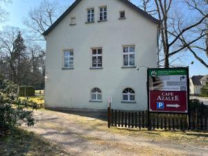 ein weißes Haus mit einem Schild davor in der Unterkunft Grüne Villa in Kromlau