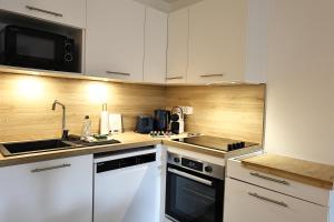 a kitchen with white cabinets and a sink and a microwave at KerTerra Corsica - Apt 3 chambres - Piscine & plage privée in Pianottoli-Caldarello