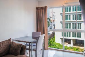 a dining room with a table and a large window at Dwija Hotel & Suite in Pattaya South