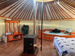 a room with two beds and a stove in a yurt at Mongolian Nomadic Herders in Dörgön