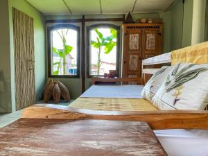 a bedroom with a large wooden bed with two windows at Casa Felina in Ilha de Boipeba