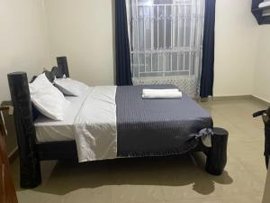 a bed with a black and white comforter and a window at Kivu Breeze Apartment in Gisenyi