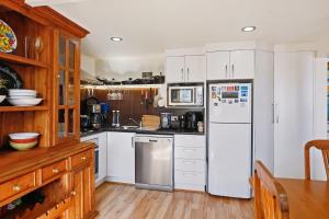 a kitchen with white cabinets and a refrigerator at Birdcage - King Bed - Walk to CBD in West Hobart +7 photos