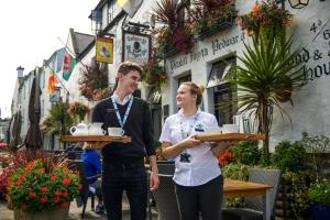 a woman holding a tray of food next to a man at The Black Boy Inn in Caernarfon
