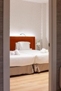 a bedroom with two beds and a wall with wallpaper at THE APARTMENT by assethoteles in Torrejón de Ardoz