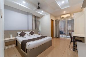 a bedroom with a bed and a desk and a window at Grace Apart Hotel @Kochi in Cochin