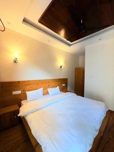 a bedroom with a large white bed with two pillows at GJ Wellness And Stay in Rishīkesh
