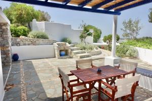 a patio with a wooden table and chairs at Villa B - Kamari Village in Aliko Beach