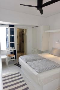 a white bedroom with a large bed and a chair at Villa B - Kamari Village in Aliko Beach
