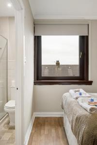 a bathroom with a bed and a window and a toilet at Glebe House in Uphall