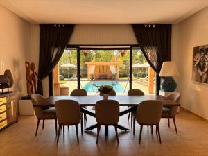 a dining room with a table and chairs and a pool at villa Bidouane in Marrakesh