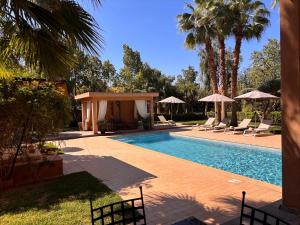 a swimming pool with chairs and umbrellas in a yard at villa Bidouane in Marrakesh