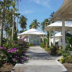 a walkway leading to a resort with purple flowers at Grand Luxcamp Pangandaran by Horison in Pangandaran