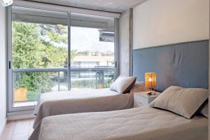 two beds in a bedroom with a large window at Oceana Suites Mansa Inn in Punta del Este