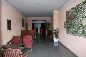 a waiting room with red chairs and a corridor at Hotel Los Naranjos in Revolta