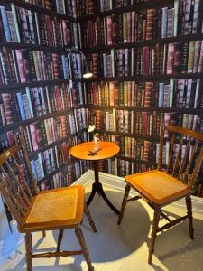 a table and two chairs in front of a wall of books at STF Landskrona Hostel in Landskrona