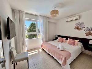 a bedroom with a bed with pink pillows and a window at Sea Point By D&G in Carilo +117 photos