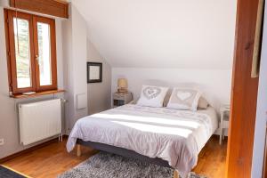 a bedroom with a bed with white sheets and a window at Studio spacieux, route des vins in Rosheim