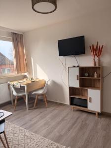 a living room with a table and a tv on a wall at Yunis Landhaus in Grömitz