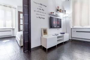 a living room with a tv and a white wall at NURAS - Joia city center in Alghero