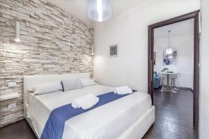 a bedroom with a white bed in a brick wall at NURAS - Joia city center in Alghero