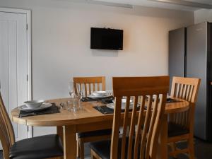 a dining room table with chairs and a television on the wall at Uk47758 - Horseshoe Cottage in Launceston