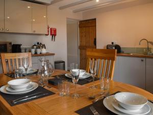 a wooden table with plates and wine glasses on it at Uk47758 - Horseshoe Cottage in Launceston