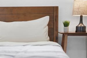 a bed with a wooden headboard and a table with a lamp at Dormont, Pittsburgh !A Spacious and Modern Private Bedroom with Shared Bathroom in Pittsburgh