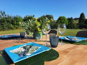 a table with wine glasses and a blue plate at Au Bon Cap in Hervelinghen