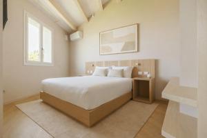 a white bedroom with a bed and a window at Portonovo Suites - Riviera del Conero in Ancona