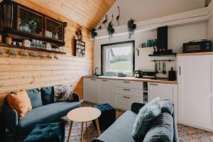 a living room with a blue couch and a kitchen at Czaplowisko - skandynawskie domy na Kaszubach in Stare Czaple