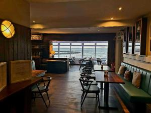 a restaurant with tables and chairs and a view of the ocean at Lochside Hotel in Bowmore