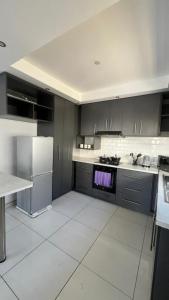 a kitchen with gray cabinets and white tile floors at CasaLisa beach House in Langstrand