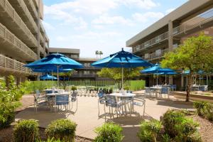 a patio with tables and chairs with blue umbrellas at DoubleTree Suites by Hilton Phoenix in Phoenix