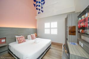 a bedroom with a large white bed and a tv at The Julia Hotel in Miami Beach