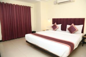 a bedroom with a large bed with red curtains at SoonStay Konark Inn in Indore