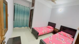 a bedroom with two beds and a window at Hotel Grand Nuria in Habiganj