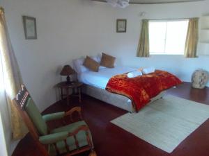 1 dormitorio con 1 cama y 1 silla en Limerick cottages, en Bulawayo