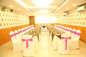 a banquet hall with tables and chairs with pink bows at SoonStay Konark Inn in Indore +3 photos