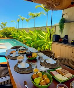 a table with food on it next to a pool at Condominio Uhane Luxury Villas in São Miguel do Gostoso