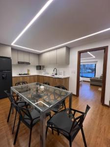 a kitchen with a glass table and black chairs at Cuenca Hotel Apartment in Cuenca