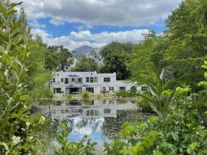 an exterior view of a house with a pond at Klein Champagne Guesthouse and Cottages in Franschhoek